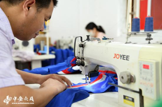 安徽省桐城市西三路城南保障小区内的东万制衣厂，工人正在制衣，章志高亲自示范